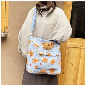 Blue canvas bag with Capybara pattern and 3D plush charm worn on a shoulder