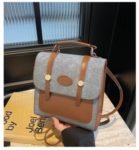 Close-up of retro grey wool and brown leather backpack with logo on marble table