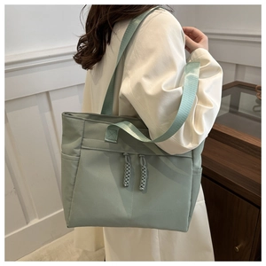 Detail view of mint green tote bag with decorative zippers and side pocket for daily use