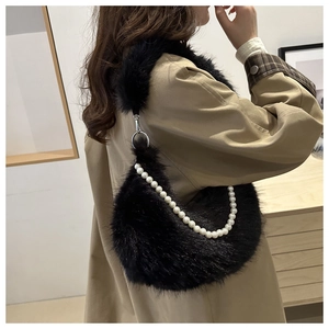 Détail d'un sac à main en peluche noire avec chaîne en perles blanches et boucle métallique