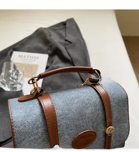 Detail of grey-blue woven fabric tote with brown leather handles and gold hardware