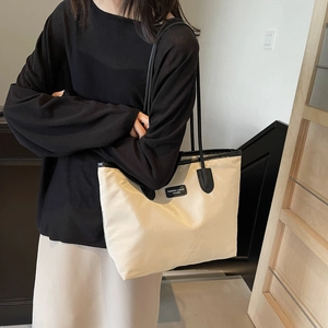 Minimalist large-capacity cream tote bag with black straps and contrast leather patch