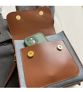 Detail of dual-tone backpack showing front pocket with gold magnetic buckles and interior capacity