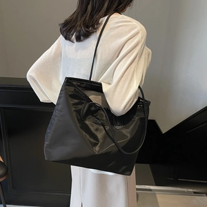 Minimalist large capacity black tote bag for daily commute shown on model's shoulder