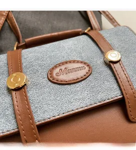 Close-up of leather and fabric patchwork with golden buckle and Manmu brand logo