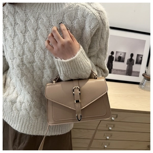 Vue détaillée du sac beige avec boucle en fer à cheval dorée et bandoulière en cuir