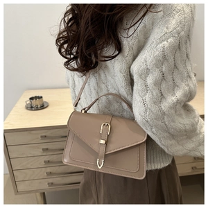 Detailed back view of a woman wearing a chic apricot leather envelope crossbody bag