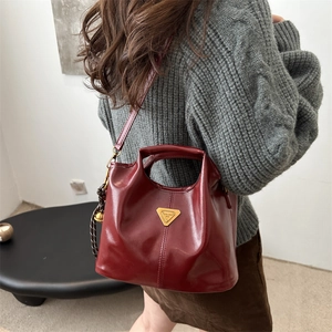 Bolso de mano retro rojo brillante con logo metálico y cadena para mujer en una habitación
