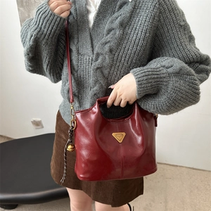 Elegante bolso de mano en cuero burdeos con herrajes dorados y correa ajustable