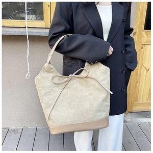 Detail of minimalist beige suede tote bag with slim leather bow and reinforced bottom