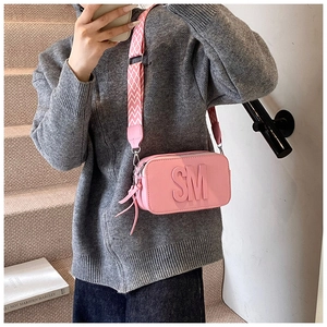 Pink crossbody bag with embossed letters and a wide geometric patterned shoulder strap