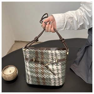 Detail of tweed checkered bucket bag with leather strap and metal buckle hardware