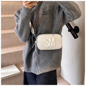 Detail of white rectangular crossbody bag with 3D SM letter logo and woven strap