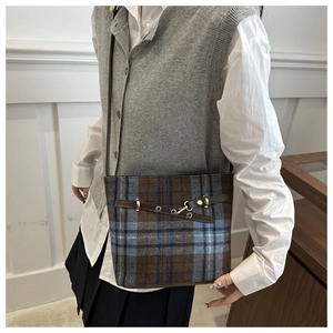 Detail of British plaid crossbody bag with leather strap and golden buckle accent