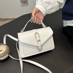 Elegant white minimalist top handle crossbody bag with golden buckle on a dark surface