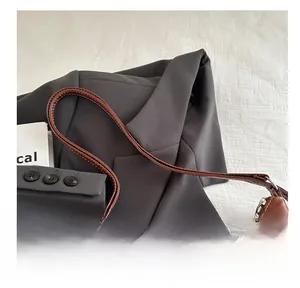 Detail of caramel brown leather tote bag showing slim shoulder strap with white stitching