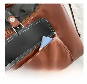 Detail of brown leather handbag with black front pocket and white contrast stitching