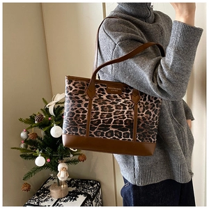 Detail of leopard print tote bag with brown leather trim and fashion brand label tag
