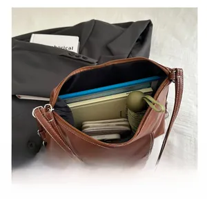 Top-down detail showing large storage capacity of brown leather tote bag with daily items