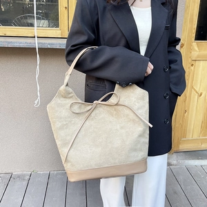Fashionable beige oversized suede tote bag with decorative bow and leather base detail