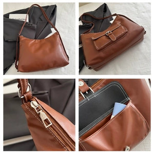Detail view of brown tote bag showing adjustable strap, metal zipper, and buckle pocket