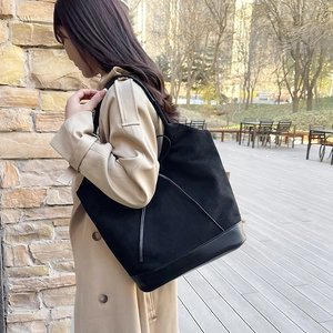 Minimalist black large capacity tote bag with suede finish worn by a model in beige coat