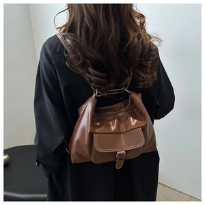 Détail d'un sac bandoulière marron chocolat en similicuir souple avec boucle en métal argenté