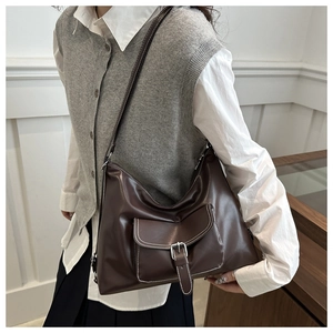 Detail of dark brown PU leather tote with white stitching and decorative buckle