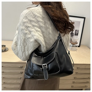 Détail du sac hobo noir avec surpiqûres blanches et poche à boucle argentée