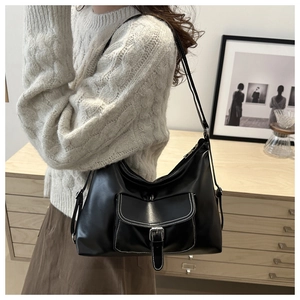Détail du sac bandoulière en similicuir noir avec surpiqûres blanches et boucle argentée