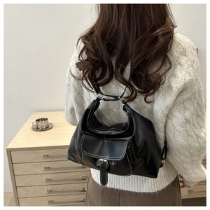 Detail view of black PU shoulder bag with white contrast stitching and silver buckle