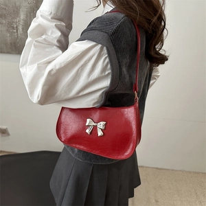 Sac à bandoulière rouge plissé vintage avec un nœud en métal argenté porté par un mannequin
