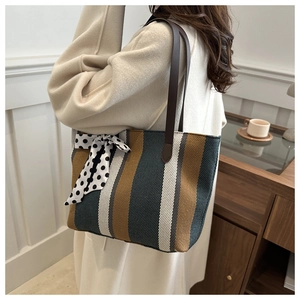 Striped canvas tote bag with polka dot ribbon and leather straps shown on shoulder
