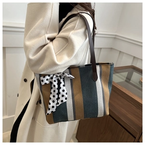 Detailed shot of striped canvas tote with leather straps and a decorative polka dot scarf