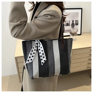 Close-up of a striped tote bag featuring a decorative silk scarf and leather handle
