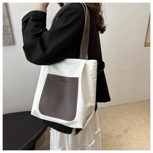 Close-up of white canvas tote bag with brown leather pocket and Budbao letter embossing