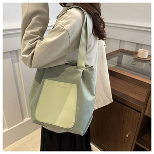 Detailed side view of a large mint green tote bag with an embossed logo pocket
