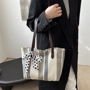 Large striped canvas tote bag with dark brown leather straps and polka dot scarf detail