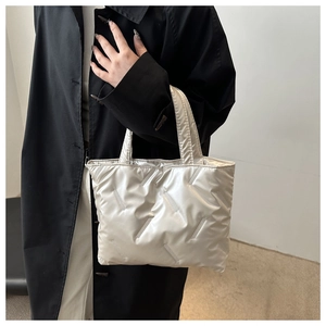 Detail of silver quilted tote bag with padded texture and metallic finish in a lifestyle shot
