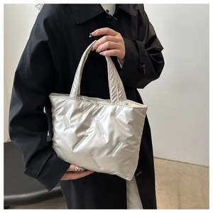Detail of silver metallic quilted tote bag with padded texture and glossy finish