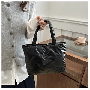 Detail of black quilted tote bag with glossy finish and soft padded stitching texture