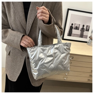 Close-up of a silver quilted tote bag with metallic finish shown in a lifestyle setting