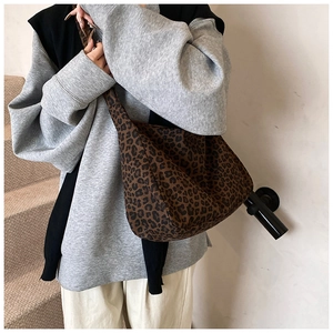 Detailed street style view of a large leopard print crossbody canvas tote bag on model