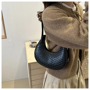 Vue latérale d'un sac à bandoulière en croissant noir avec texture tressée sur modèle
