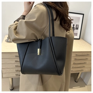 Detail einer schwarzen matten Leder-Tote-Bag mit goldener Schließe an einem Modell