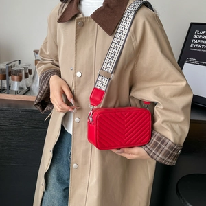 Piccola borsa a tracolla rossa trapuntata a V con tracolla jacquard indossata da modella