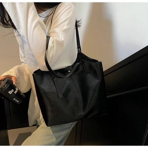Detailed view of black oil wax leather tote bag worn by model in urban street style