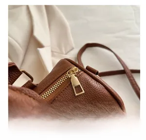 Close-up of smooth gold metal zipper on brown pebble leather boston handbag