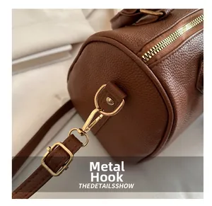 Detail view of premium brown pebble leather texture and golden metal hardware on the bag