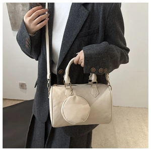 Detail of creamy white Boston bag with litchi texture and round coin purse charm